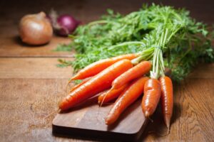 Article: Companion Plants for Carrots. Carrots lying on a chopping boards