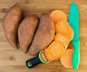 sweet potato 3 whole 1 sliced on a chopping board green knife