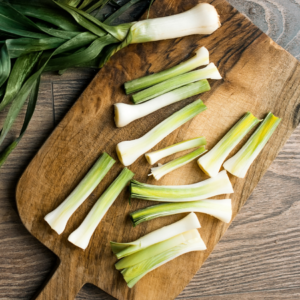 Article: Companion plants for leeks Pic - "Sliced leeks arranged on a wooden cutting board, showcasing the vegetable's transition from whole to cut, ready for cooking."