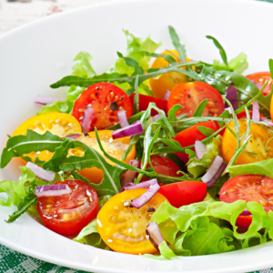 "A vibrant bowl of arugula and multi-colored tomato salad with red onion slices."