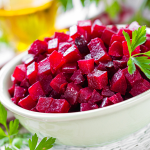 A bowl of freshly diced beetroot garnished with parsley on a kitchen table.