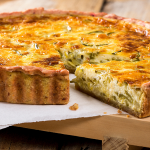 Article: Companion plants for leeks, Pic- A golden-baked leek pie with a slice cut out, revealing layers of tender leeks encased in a flaky crust
