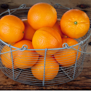  A wire basket filled with fresh, bright oranges on a wooden surface.