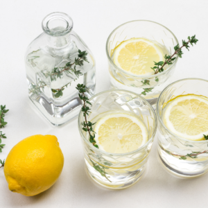 Article: Thyme Companion Plants. "Three glasses with sprigs of thyme and lemon slices, next to a clear bottle and a whole lemon, ready for a zesty concoction.