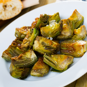 Roasted artichoke hearts on a white plate, beautifully caramelized and sprinkled with sea salt.