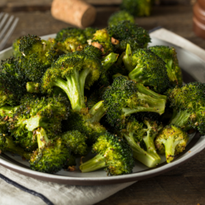 Roasted broccoli florets on a plate, seasoned with garlic and herbs.