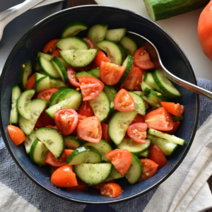 Article: Low Oxalate Foods To Plant With Green Bell Peppers. Pic - A fresh cucumber salad garnished with herbs and colorful peppercorns in a white bowl.