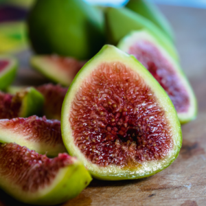 Close-up of a halved fig with a vibrant red interior, surrounded by other halved and whole figs.