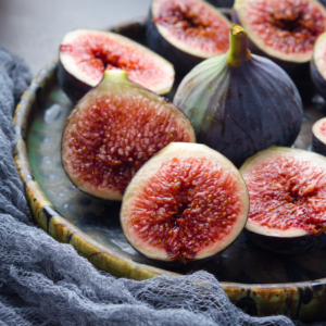 Close-up of halved figs arranged on a rustic plate, showcasing their juicy red interiors.