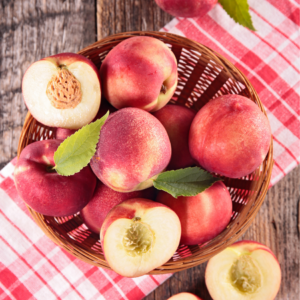 A basket of ripe nectarines on a rustic wooden table, with some nectarines cut in half to reveal their juicy interior and pits.