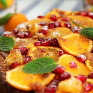 Article: Growing a Pomegranate Tree in a pot. Pic - Close-up of a dessert topped with sliced oranges, pomegranate seeds, and mint leaves.