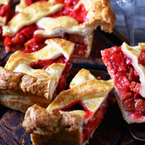  Slices of rhubarb pie with a golden, flaky crust on a wooden cutting board.