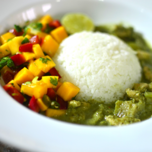 Article: Papaya Enzymes for digestion. Pic  - A white plate with a serving of rice, green curry, and a colorful mango and red bell pepper salsa.