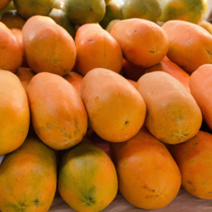 A pile of ripe papayas with yellow-orange skin displayed at a market.