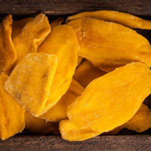 A close-up of dried papaya slices with a vibrant orange color, arranged in a wooden container.